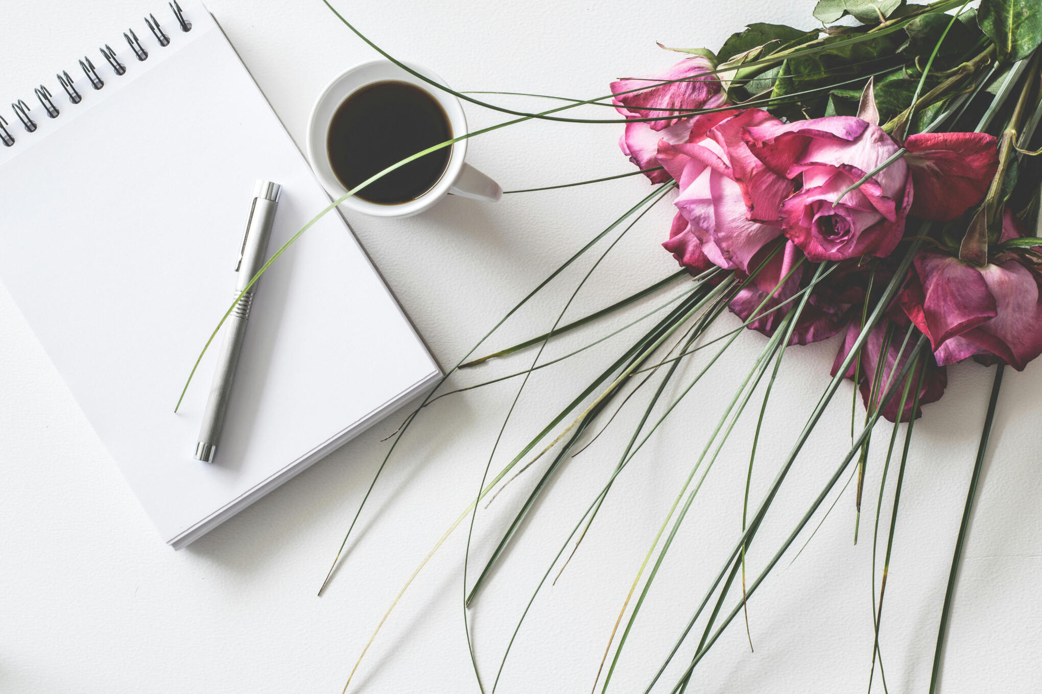 white coffee cutup with blank page and pen bouquet of roses